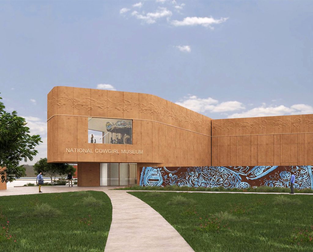 A modern tan building labeled National Cowgirl Museum features a mural with blue designs, a large window with an artwork, a curved path, green grass, and a partly cloudy sky.