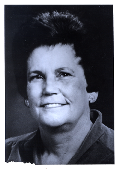 Studio portrait of a smiling middle-aged woman with short dark hair and earrings.