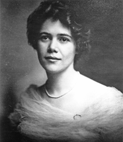 Black-and-white studio portrait of a woman wearing an elegant off-shoulder gown and feathered shawl.