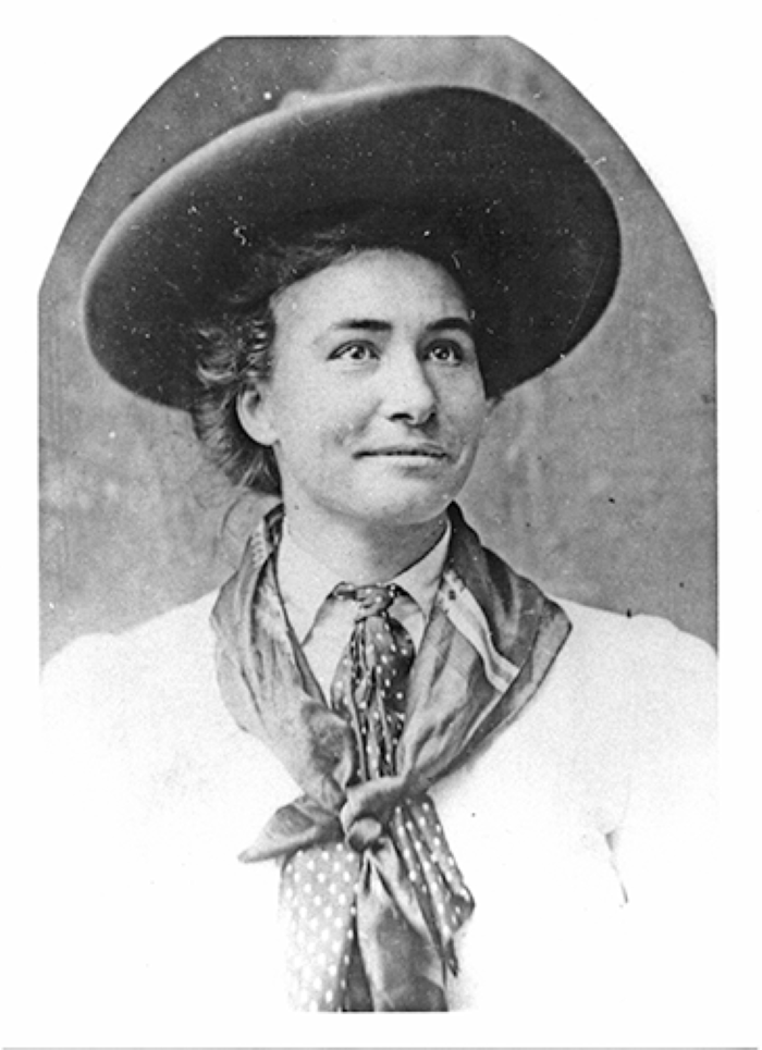 Portrait of a woman in a wide-brimmed hat and polka-dot scarf, posing for a vintage-style photo.