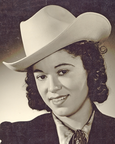 Vintage portrait of a woman with dark curly hair wearing a white cowboy hat and neckerchief