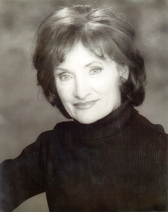 Black-and-white portrait of a smiling woman with short hair wearing a dark turtleneck.