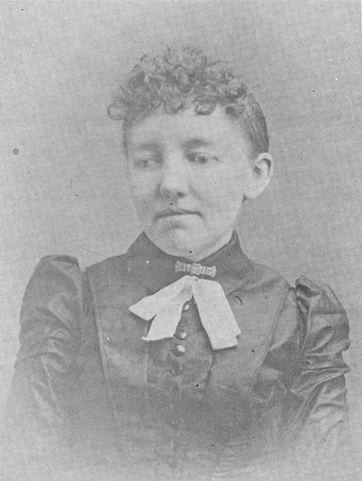Portrait of a young girl in a dark Victorian dress with a white bow at the neckline, posed for a formal 19th-century photograph.