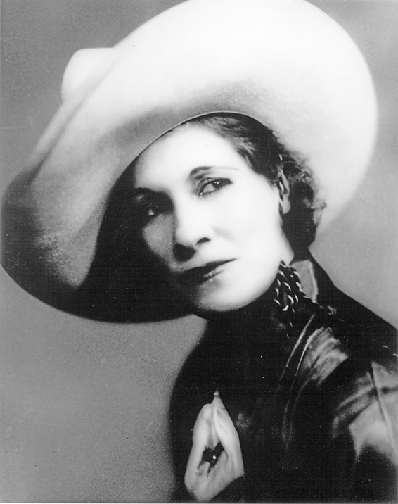 Black-and-white portrait of a woman wearing a large, wide-brim hat, looking to the left.