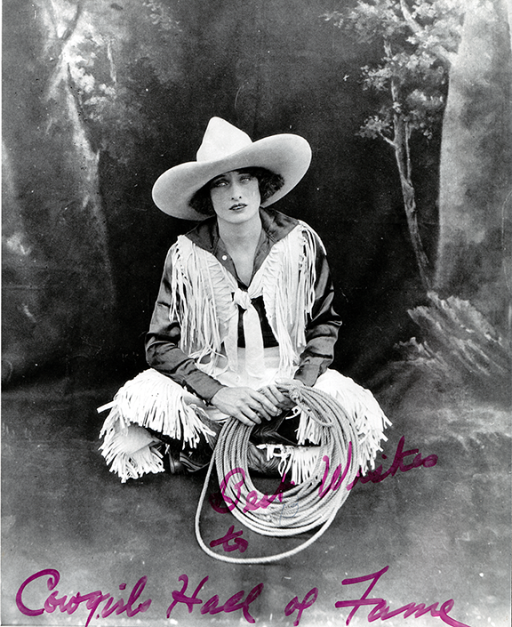 Black-and-white portrait of a cowgirl in a wide-brimmed hat and fringed jacket, holding a coiled lasso, with 'Cowgirls Hall of Fame' script at the bottom.
