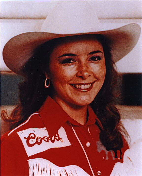 Smiling woman in a white cowboy hat and red fringed Western shirt with a name patch reading Connie.