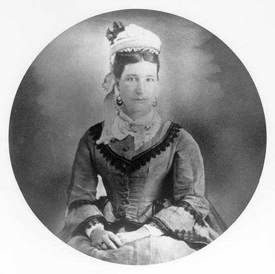 Portrait of a Victorian-era woman in a formal dress with a bonnet, seated and facing the camera.