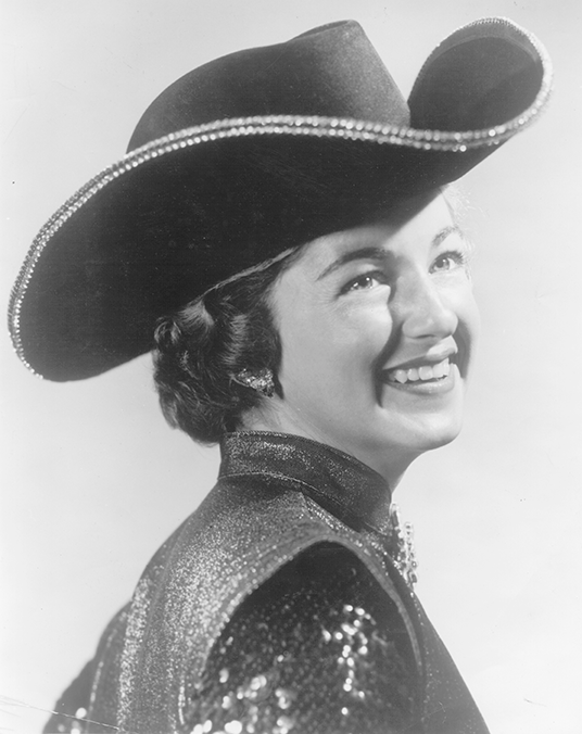 Black-and-white portrait of a smiling woman wearing a wide-brimmed cowboy hat.